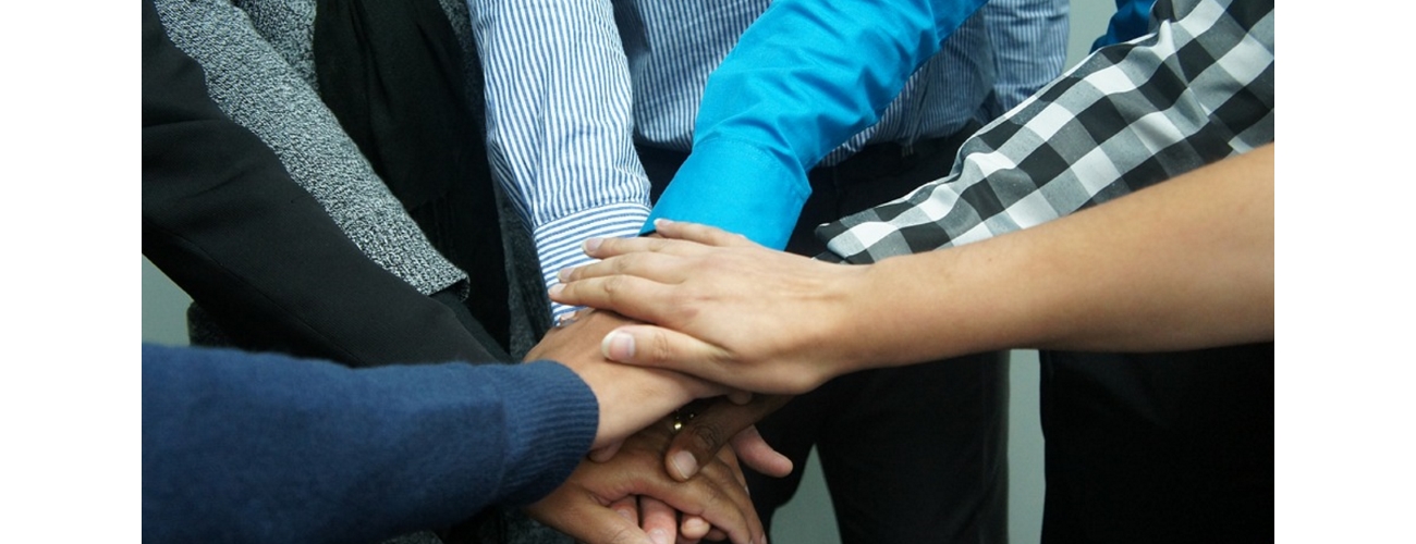 Group of people piling hands to evoke unity/teamwork.